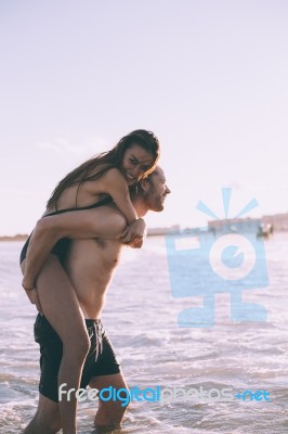 Couple Is Piggybacking On The Beach Stock Photo