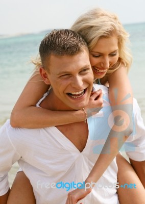 Couple Piggyback Ride At Beach Stock Photo