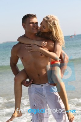 Couple Piggyback Ride At Beach Stock Photo