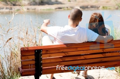 Couple Sitting At Lake Side Stock Photo