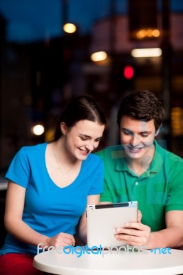 Couple Using Digital Tablet In Cafe Stock Photo