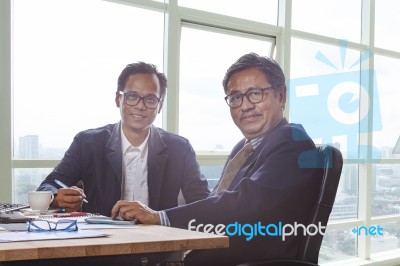 Couples Of Business Man Working On Office Working Table With Smiling Face Looking To Camera Stock Photo