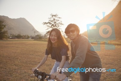 Couples Of Younger Asian Man And Woman Practice To Riding Bicycle In Natural Field Relaxing Emotion Stock Photo