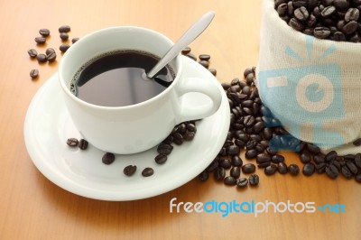 Cup Of Coffee And Bag Beans On Wooden Table Stock Photo