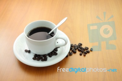 Cup Of Coffee With Beans On Wooden Table Stock Photo