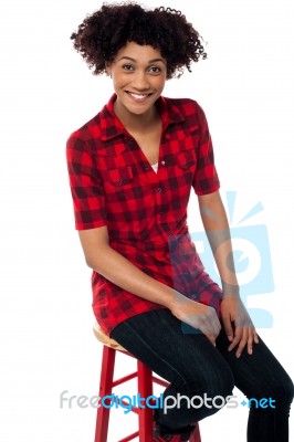 Curly Haired Fashion Model Sitting On Red Stool Stock Photo