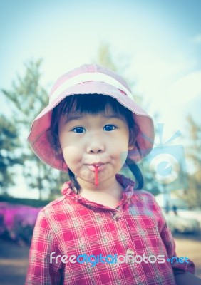 Cute Little Asian Girl Eating A Lollipop On Nature Background In… Stock Photo