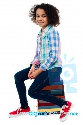 Cute School Girl Sitting On Stack Of Books Stock Photo