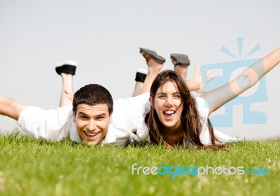 Cute Young Couple Lie Down On Grass Stock Photo