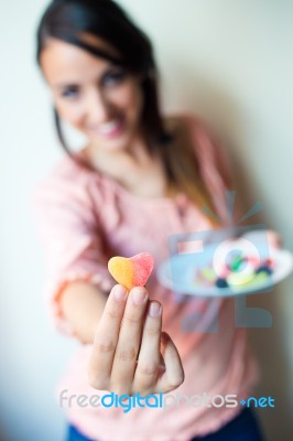 Cute Young Woman Eating Jelly Candies With A Fresh Smile Stock Photo