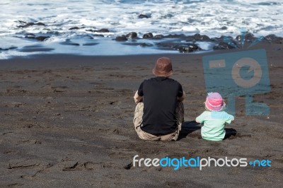 Dad And Daughter Watching The Waves Stock Photo