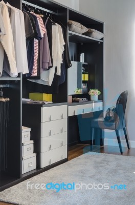 Dark Color Scheme Modern Walk In Closet Design With Black Chair Stock Photo