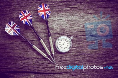 Darts And Watch On Old Wooden Background. Vintage Style Stock Photo