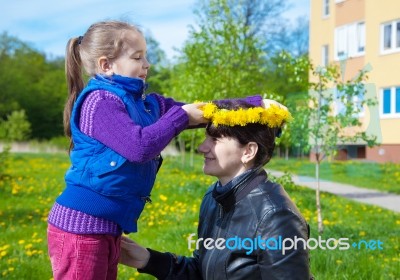 Daughter Puts On Her Mom's Head A Wreath Of Dandelions Stock Photo