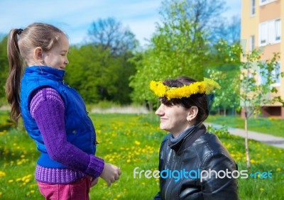 Daughter Puts On Her Mom's Head A Wreath Of Dandelions Stock Photo