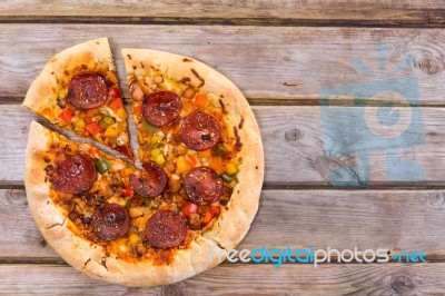 Delicious Baked Salami Pizza Served On Rustic Wooden Table Stock Photo