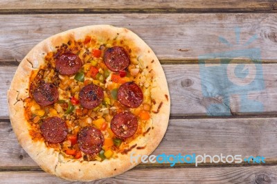 Delicious Baked Salami Pizza Served On Rustic Wooden Table Stock Photo