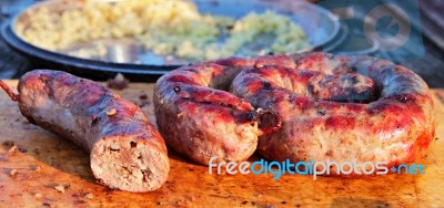 Delicious Sausages On Wooden Plate Cooked On Barbecue Grill Stock Photo