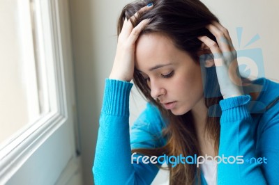 Depressed Young Woman Sitting At Home Stock Photo