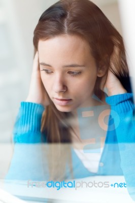 Depressed Young Woman Sitting At Home Stock Photo