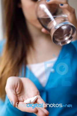 Depressed Young Woman Taking Pills At Home Stock Photo