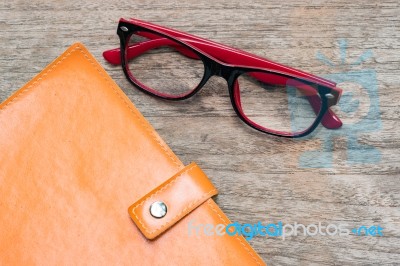 Diary Booklet And Eye Glasses On Wooden Desk Stock Photo