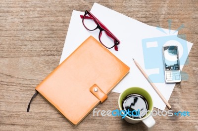 Diary,blank Paper With Pencil, A Cup Of Coffee, Mobile Phone And Eye Glasses On Wood Table Stock Photo