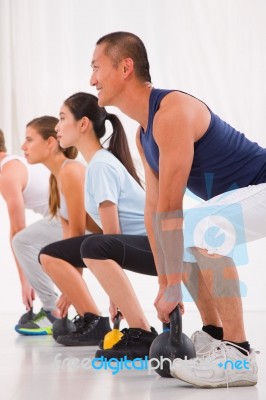 Diverse Group Practicing Kettlebell Exercise In Crossfit Gym Stock Photo