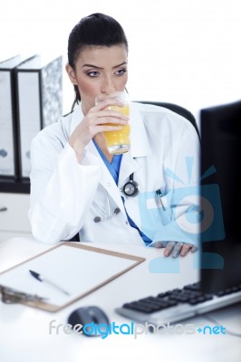 Doctor Drinking A Glass Of Juice At Her Workplace Stock Photo