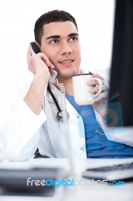 Doctor Talking Over Telephone And Having Coffee Stock Photo