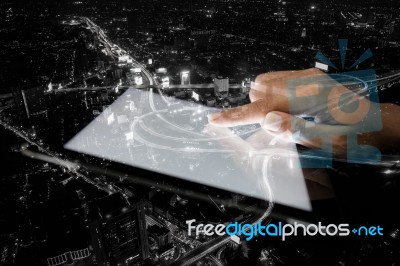 Double Exposure Hand Using Tablet And City On Night Background Stock Photo