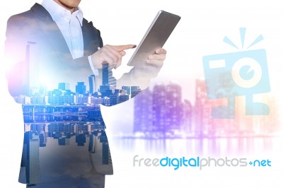 Double Exposure Of Businessman Holding Tablet With Cityscape Blurred Background, Business Concept Stock Photo