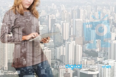 Double Exposure Of Woman Using Tablet Technology And Urban Building Background Stock Photo