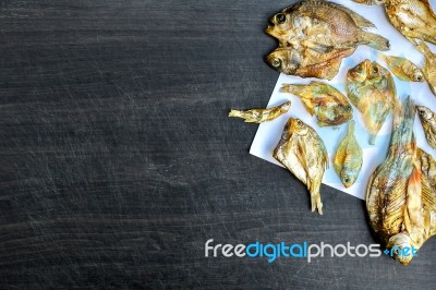 Dry Fish With Sunny On Black Wooden Floor Stock Photo