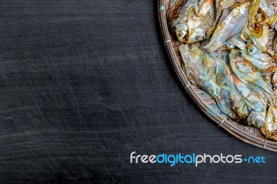 Dry Fish With Sunny On Black Wooden Floor Stock Photo