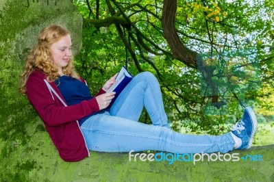 Dutch Girl Lying Reading Book In Green Tree Stock Photo