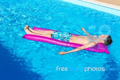 Dutch Teenage Boy Lying  On Air Mattress In Swimming Pool Stock Photo