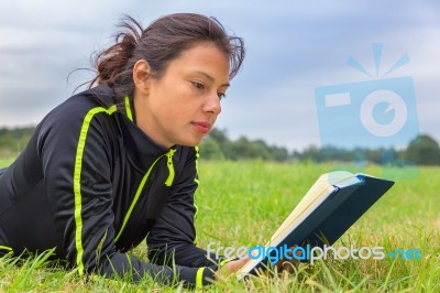 Dutch Woman Lying In Grass Reading Book Stock Photo