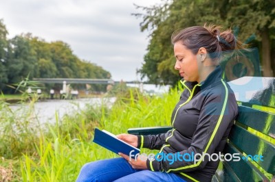 Dutch Woman On Bench At Water Reading Book Stock Photo