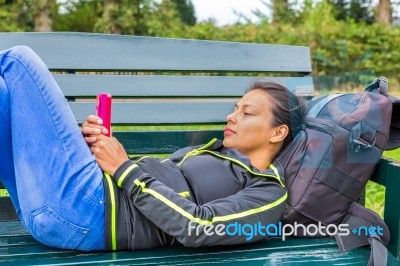 Dutch Woman Operating Mobile Phone Lying On Bench Stock Photo