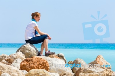 Dutch Woman Sitting On Rocks With Blue Sea Horizon Stock Photo