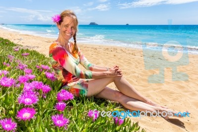 Dutch Woman With Pink Flowers On Sandy Beach With Blue Sea At Co… Stock Photo