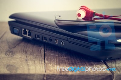 Earphones And Smart Phone On Laptop Stock Photo