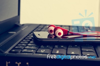 Earphones And Smart Phone On Laptop Stock Photo