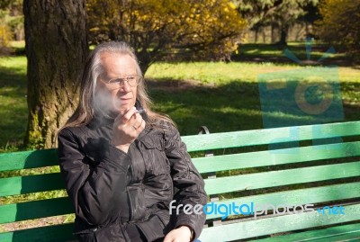 Elderly Gray-haired Man In Glasses Smoking A Cigarette In City P… Stock Photo