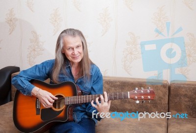 Elderly Man Playing The Guitar At Home Stock Photo