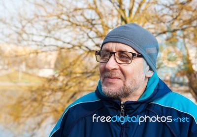 Elderly Man Wearing Glasses, A Gray Hat And Blue Jacket In A Cit… Stock Photo