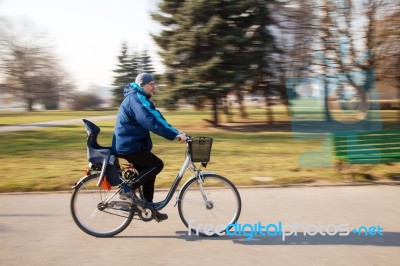 Elderly Man Wearing Glasses Riding A Bicycle Fast Stock Photo