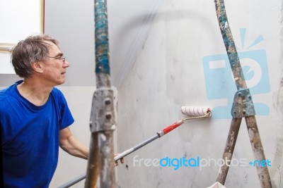 Elderly Worker Painting Wall With Glue Stock Photo