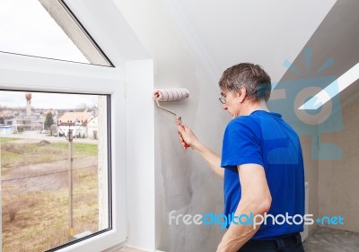 Elderly Worker Painting Wall With Glue Stock Photo